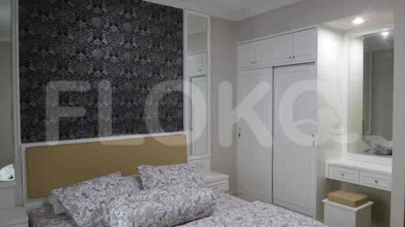 A cozy bedroom with a queen-sized bed, patterned wallpaper, and a built-in wardrobe.