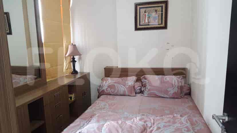 A cozy bedroom with a double bed, a dresser, and a table lamp.