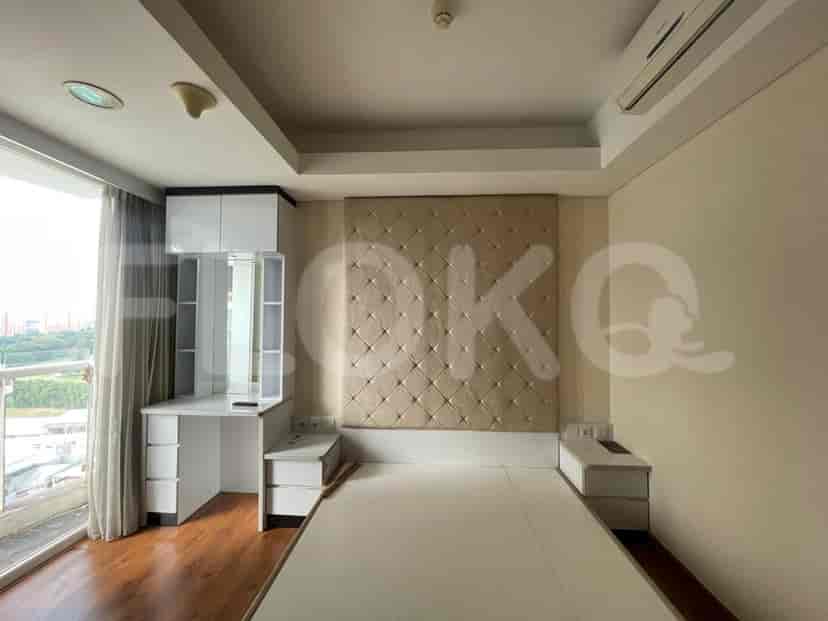 A bedroom with a bed, desk, and large window.
