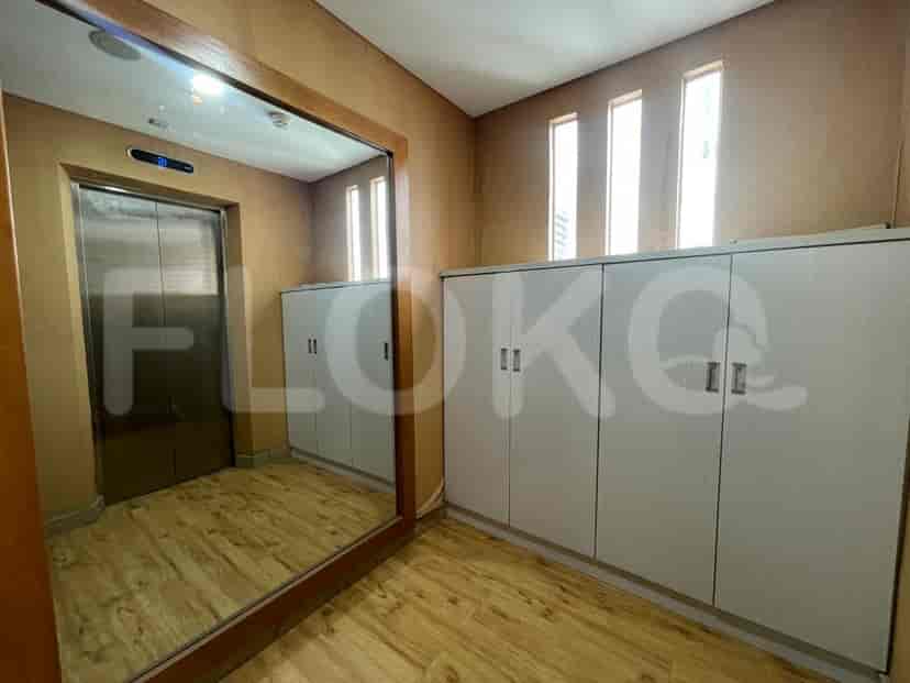 A hallway with a mirror, cabinets, and an elevator.