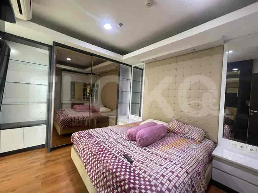 A bedroom with a bed, sliding closet, and a large mirror.