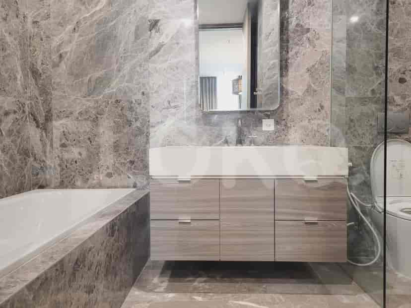 Bathroom with a vanity, bathtub, and marble wall.