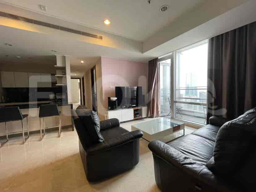 Modern living room with black leather furniture, a white coffee table, and a view of the city.