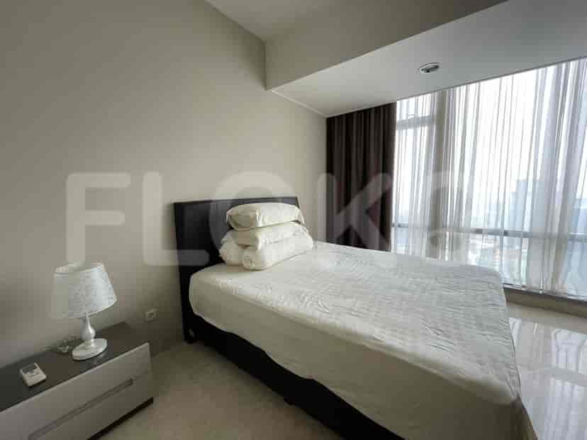 Bedroom with large windows, a bed, and a view of the city.