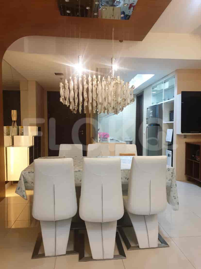 A dining room with a large table, six white chairs, and a decorative chandelier.