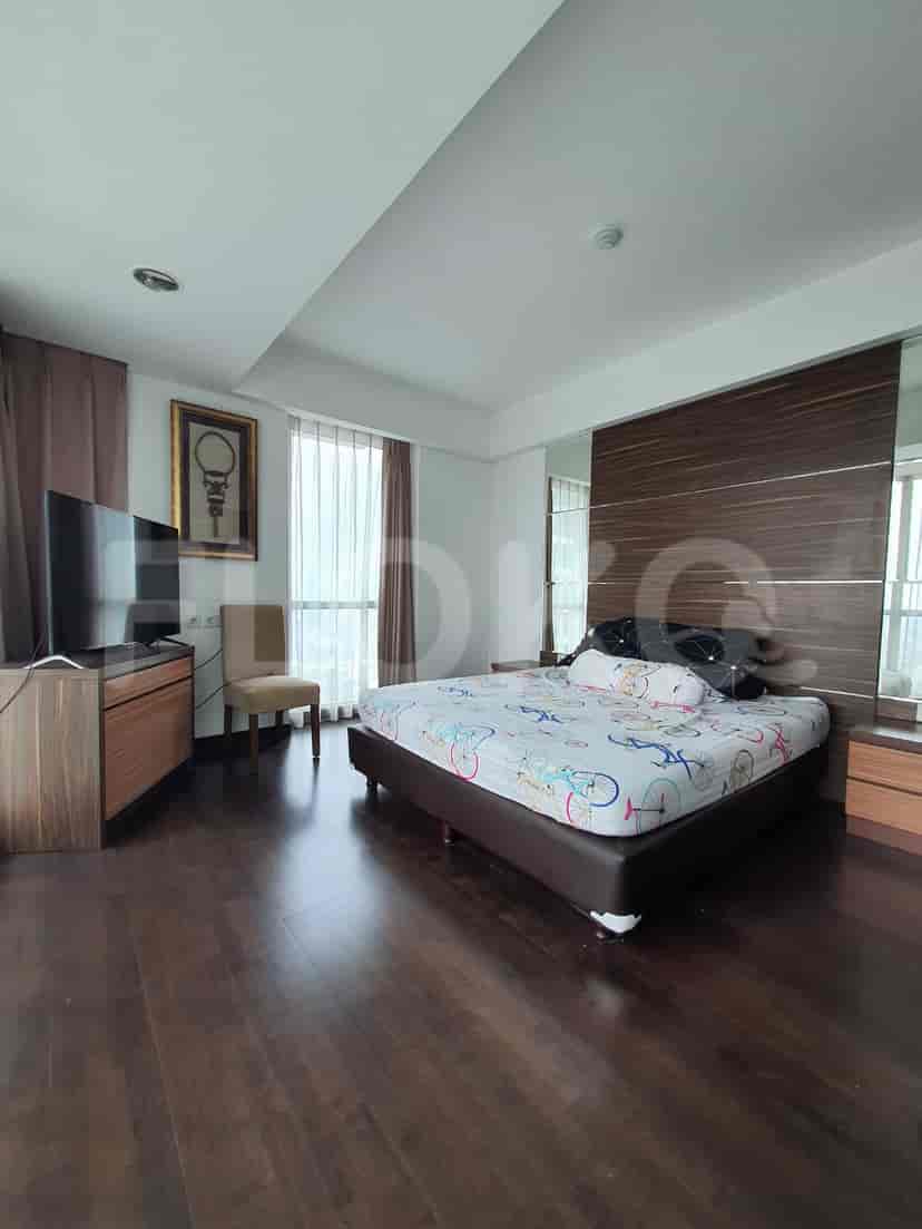 A bedroom with a bed, TV, and large windows.