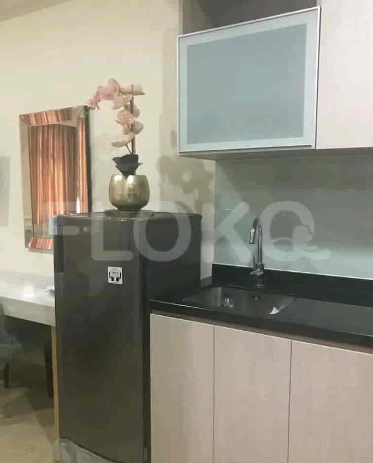 A kitchenette with a refrigerator, sink, and cabinets.
