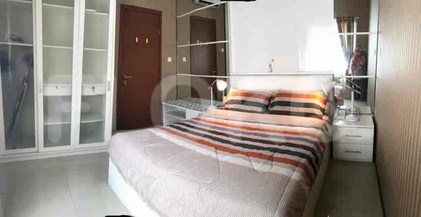 A well-lit bedroom with a bed, wardrobe, and a side table with a lamp.