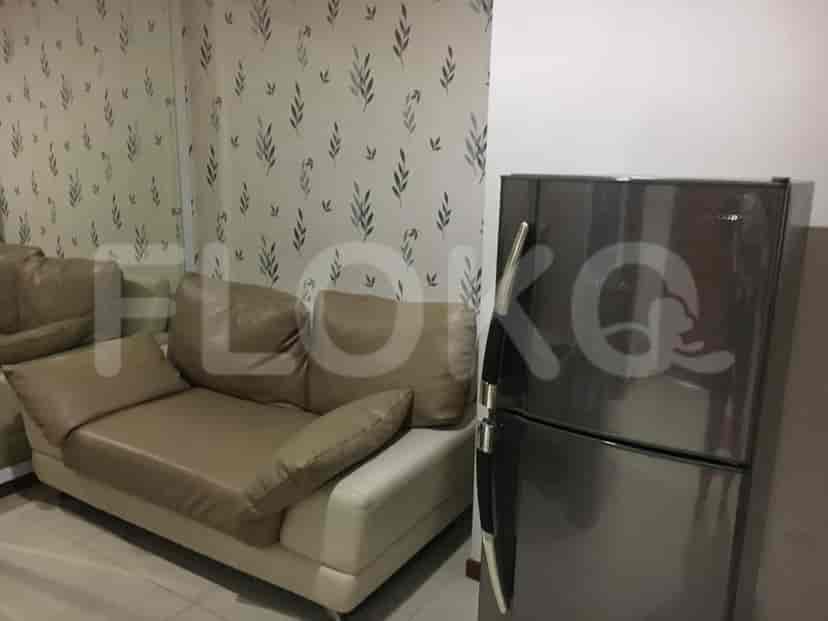 A living area with a sofa, refrigerator, and patterned wallpaper.