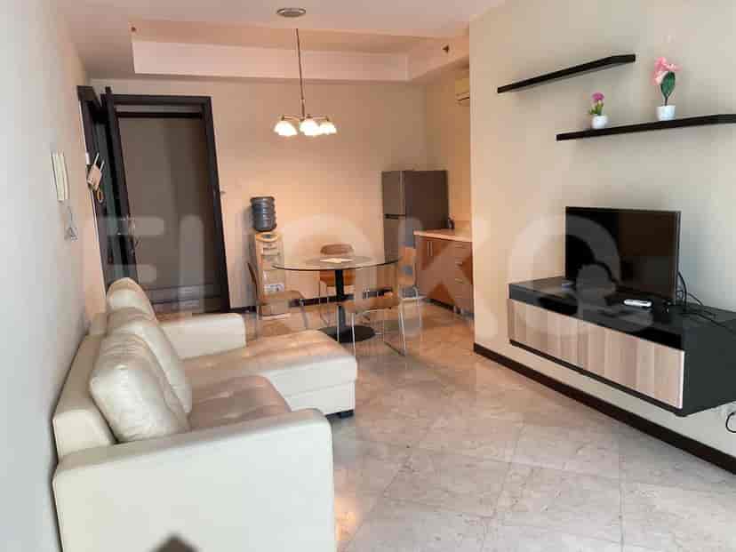 A living room with a white sofa, dining area, and TV on a black stand.