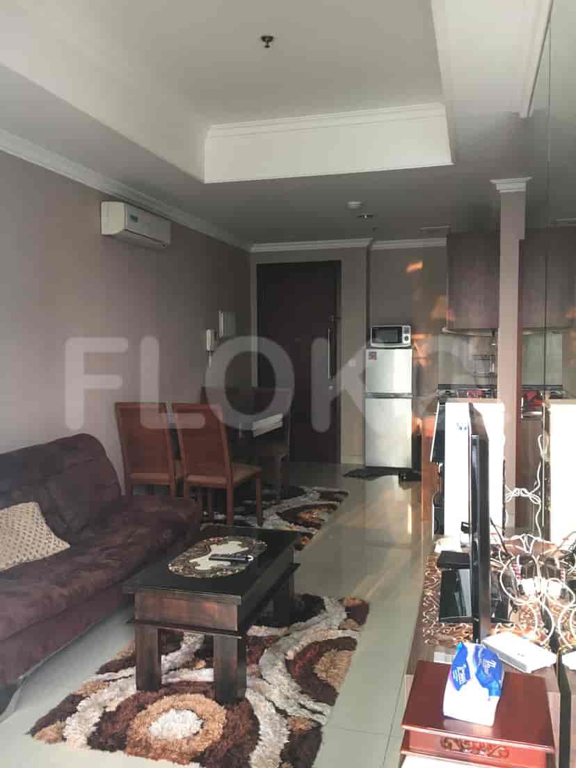 A combined living and kitchen area, featuring a sofa, dining table, and kitchen appliances.