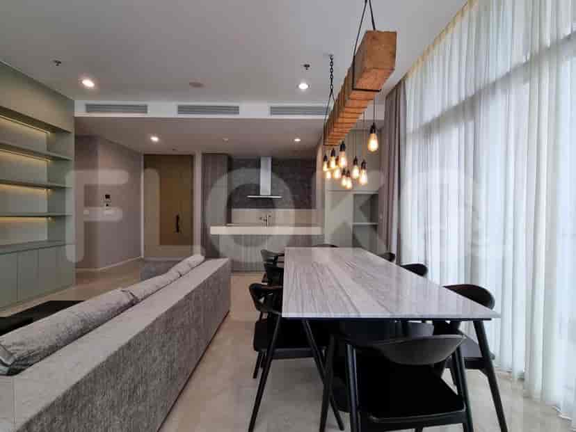 An open plan living and kitchen area featuring a dining table and light fixtures.