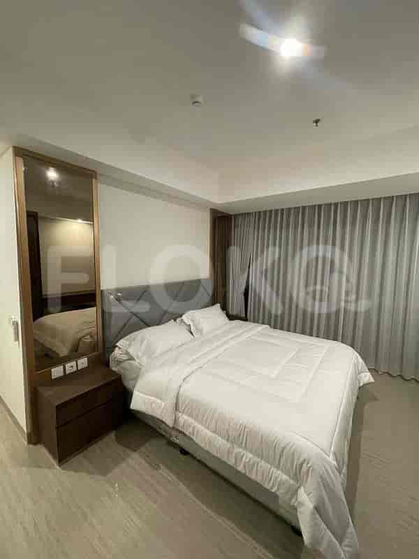 A well-lit bedroom featuring a bed, a mirror, and a nightstand.