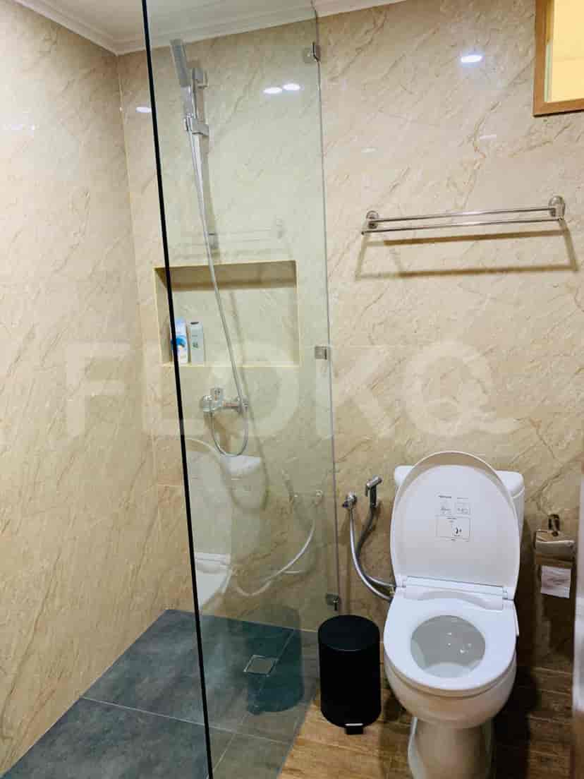 A modern bathroom with a glass shower, toilet, and marble walls.