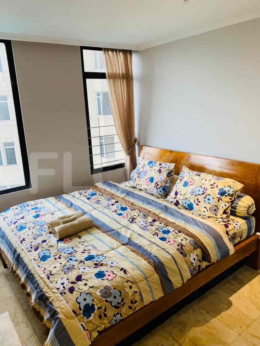 Bedroom featuring a wooden bed with patterned bedding, large windows, and neutral-colored walls.