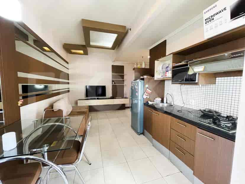 Open kitchen with a refrigerator, cabinets, and a small dining area.