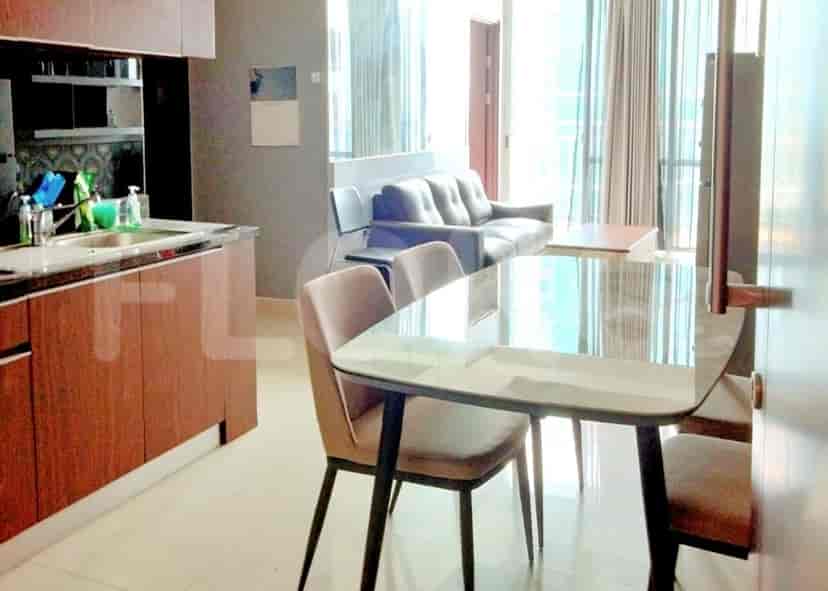 A dining area with a glass table, chairs, and open kitchen.
