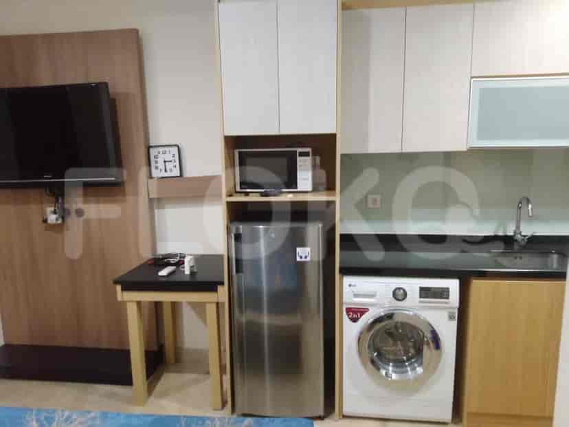 A combined living and kitchen area featuring a TV, microwave, refrigerator, and washing machine.