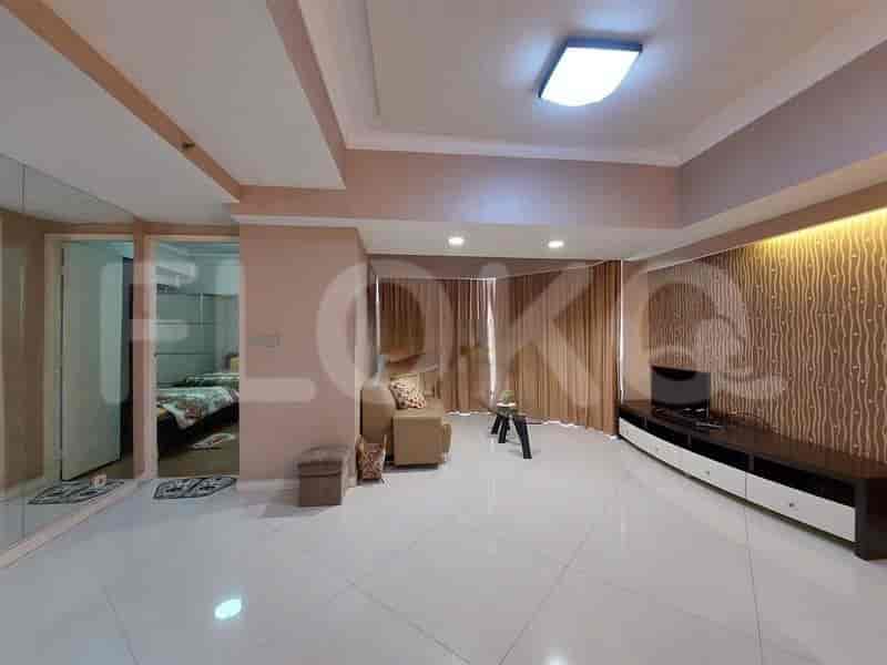 A living room with a sofa, TV, and white tile flooring.