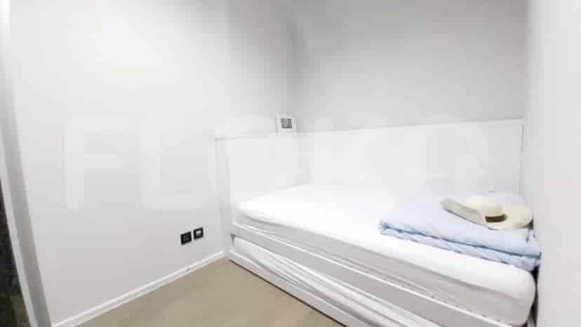 A second bedroom with a single bed, a minimalist design, and a hat laid on the bed.