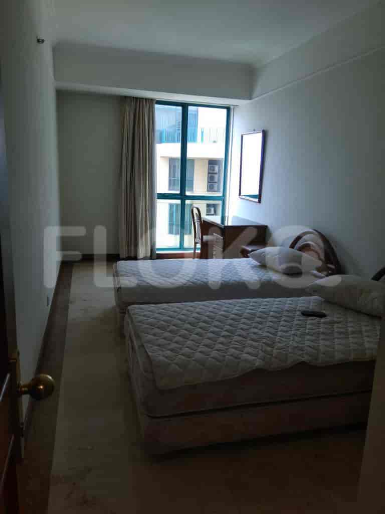 A small bedroom with two twin beds, a desk, and a large window.