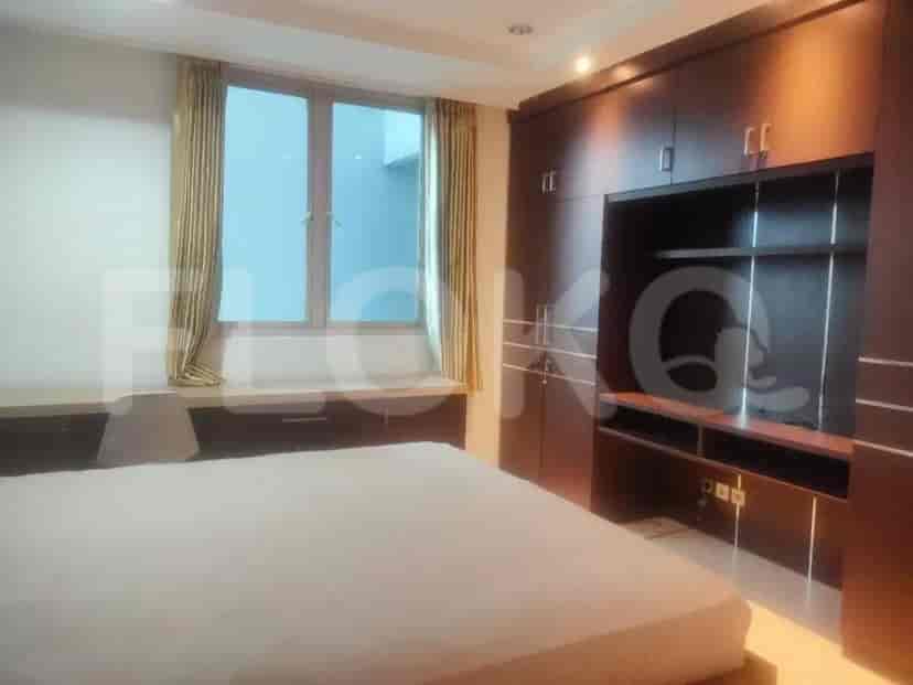 A bedroom featuring a built-in wardrobe, desk, and a large window with curtains.