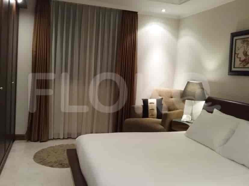 A bedroom with a large bed, a sitting area, and neutral-toned curtains.