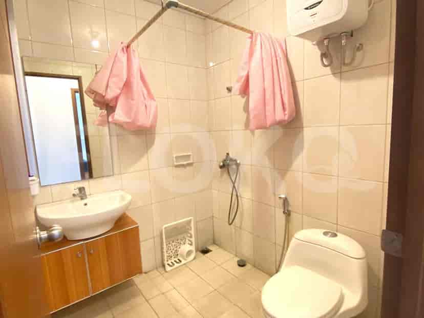 Kamar mandi kecil dengan toilet, wastafel, dan area shower dengan tirai shower merah muda.