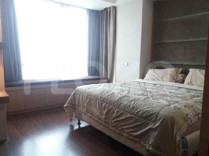 A bedroom with a large bed, a window seat, and a large window.