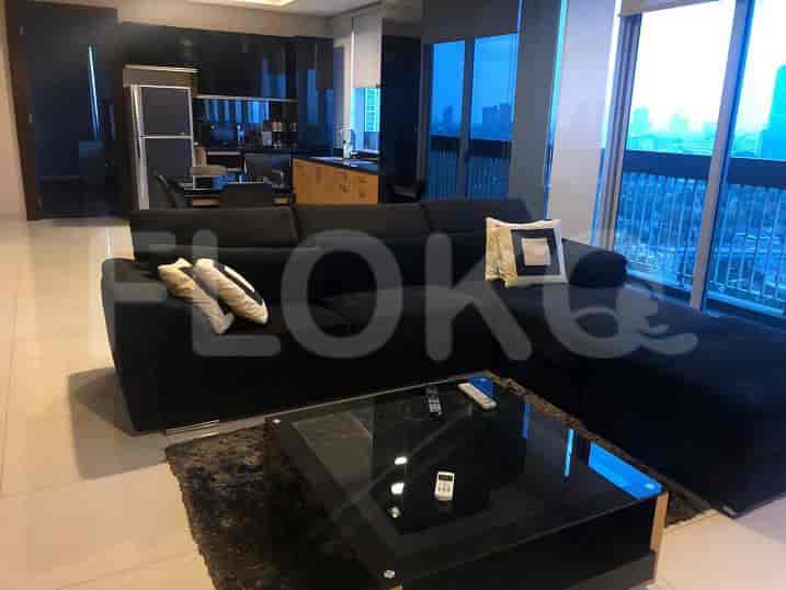 A view of the living room showcasing a black L-shaped sofa, a coffee table, and a city view.