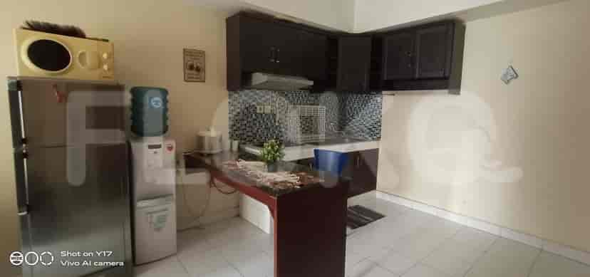 A kitchen with a fridge, cabinets, and a bar.