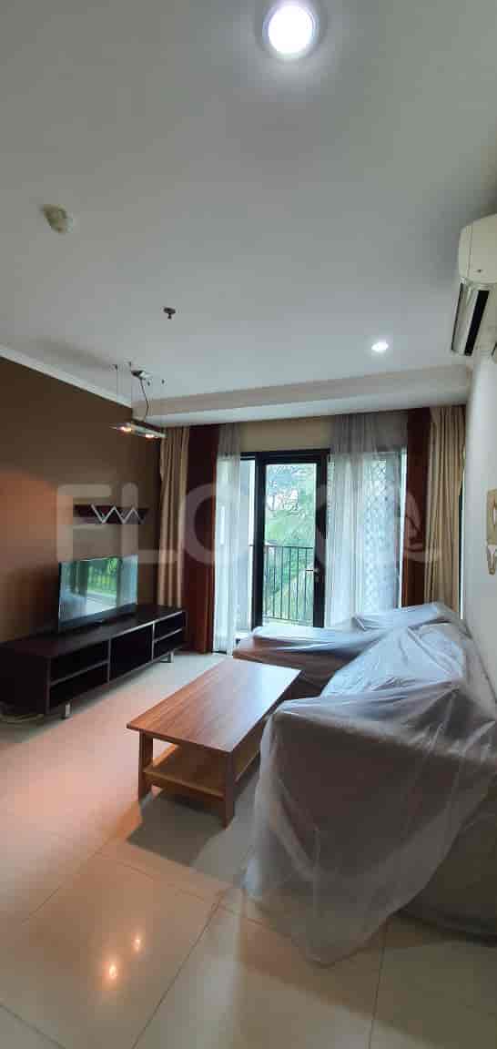 A living room with a TV, a sofa covered in plastic, and a balcony door.