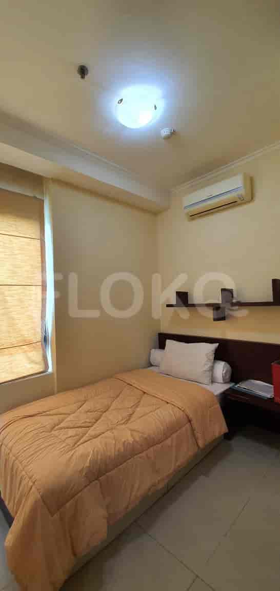A cozy bedroom with a single bed, a side table, and a wall-mounted AC.