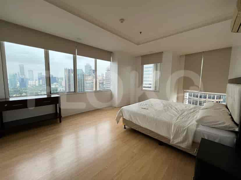 A bedroom with a large bed, a desk, and a window overlooking a cityscape.