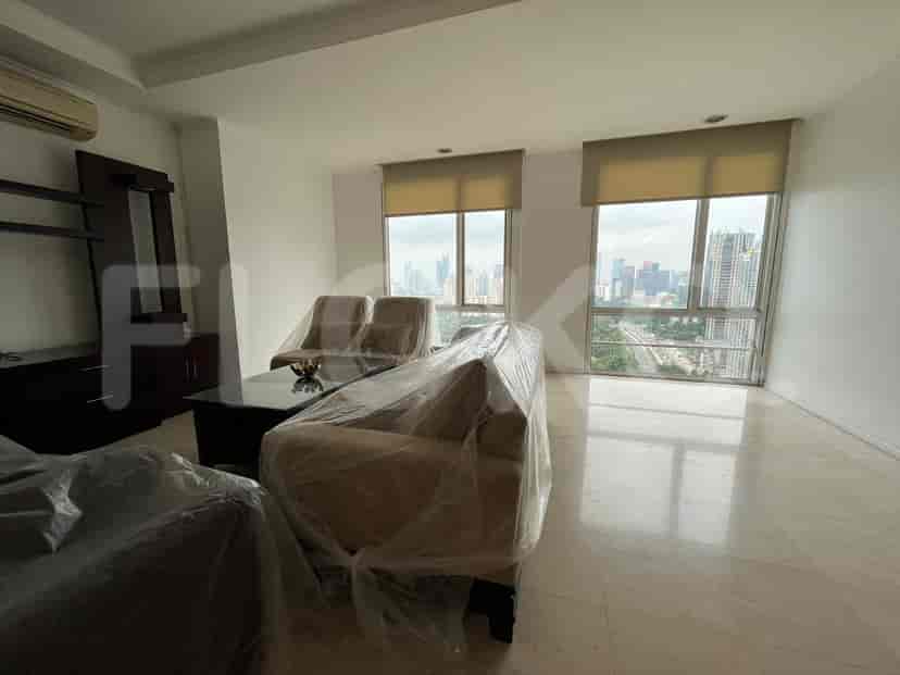 A living room with sofas covered in protective plastic, a coffee table, and large windows with a city view.