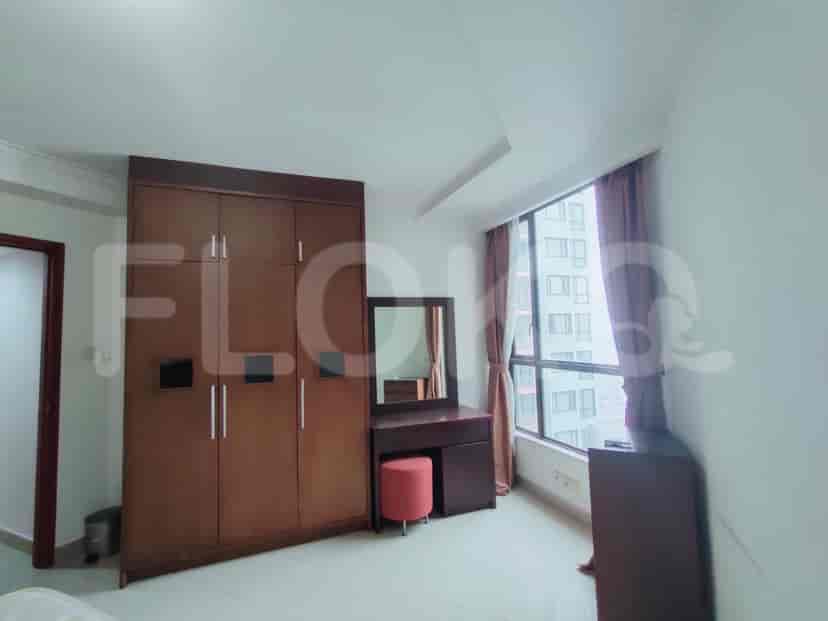 A bedroom featuring a wardrobe, a vanity with a mirror, and a window with curtains.