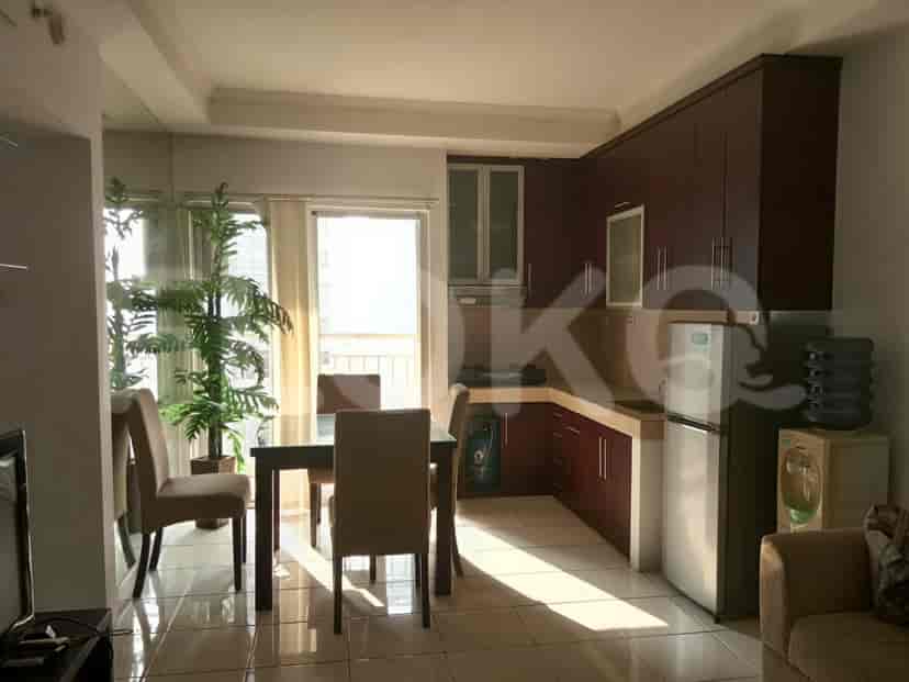 A living room and a kitchen with a dining area, with a refrigerator and water dispenser.