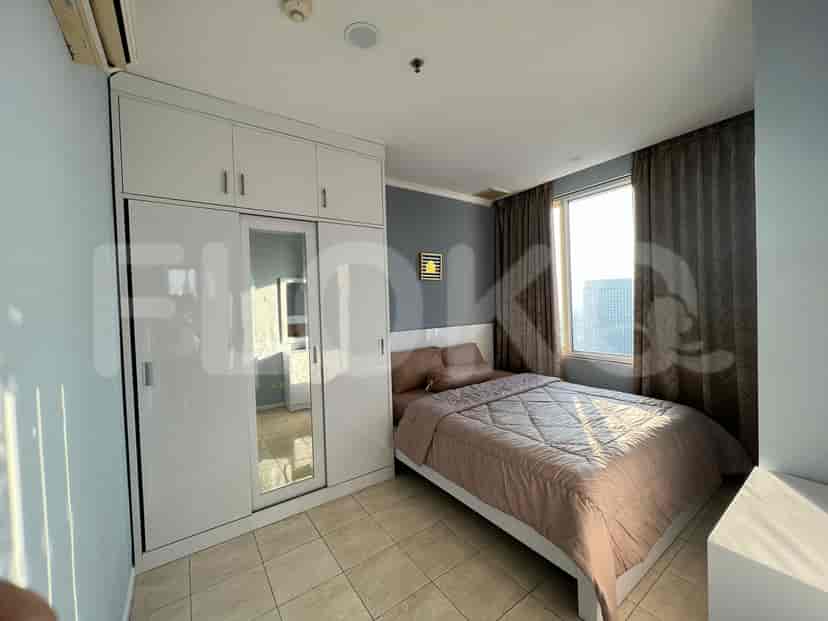 A bedroom with a queen-size bed, built-in wardrobe with mirrored doors, and a window with city views.