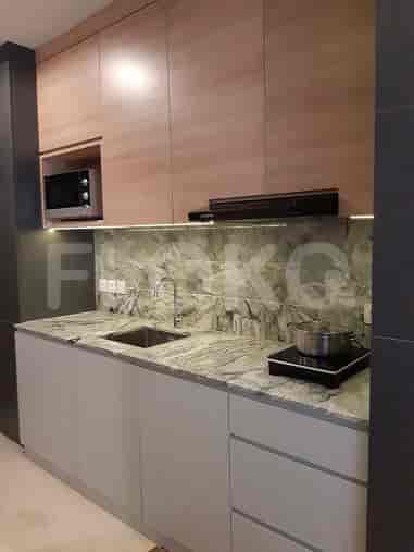 A modern kitchenette with light-colored cabinets, granite countertop, and cooking facilities.