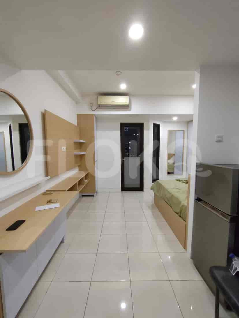 Small apartment showing the bed, kitchen area, and entertainment unit.