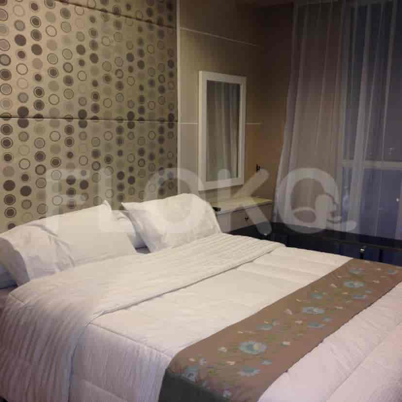 Sebuah kamar tidur dengan tempat tidur ukuran queen, seprai putih, dan kepala tempat tidur berpola dekoratif.