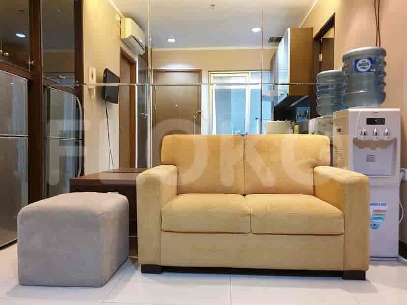 A living room with a yellow sofa and a small table.