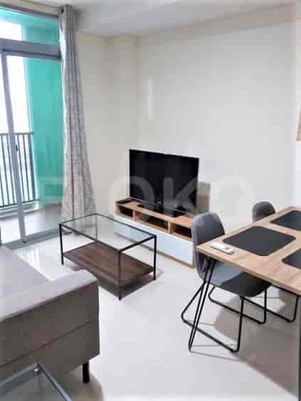 A living room featuring a TV unit, glass coffee table, dining set, and balcony access.