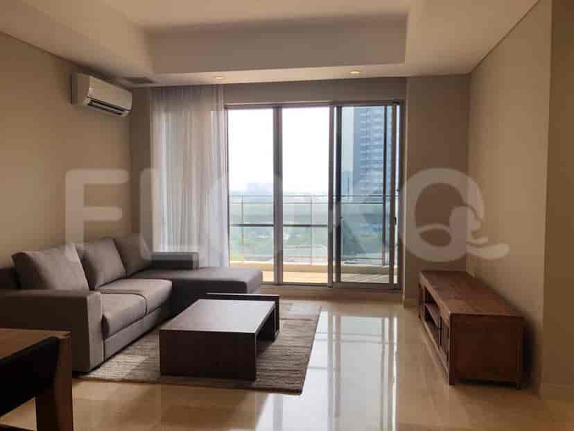 A modern living room with a grey sofa, coffee table, and large windows.