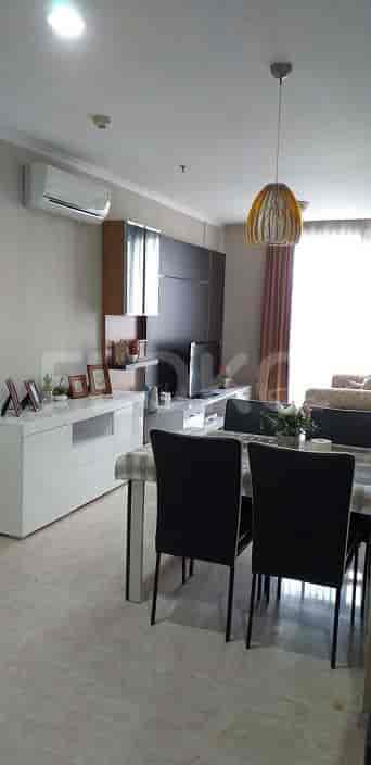 A well-lit living room with a dining area, featuring a TV, cabinet, and a dining table.