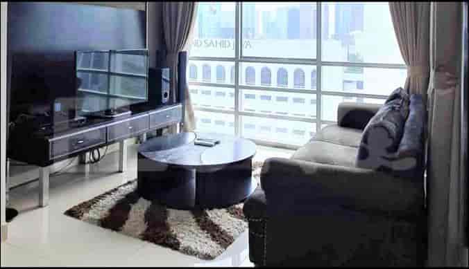 A modern living room featuring a grey sofa, TV console, and large windows.