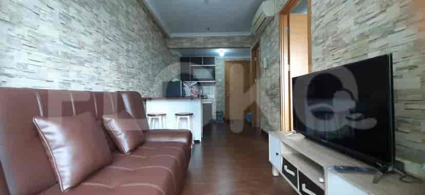 Living room with brown leather sofa, TV on a stand, and a kitchen bar.