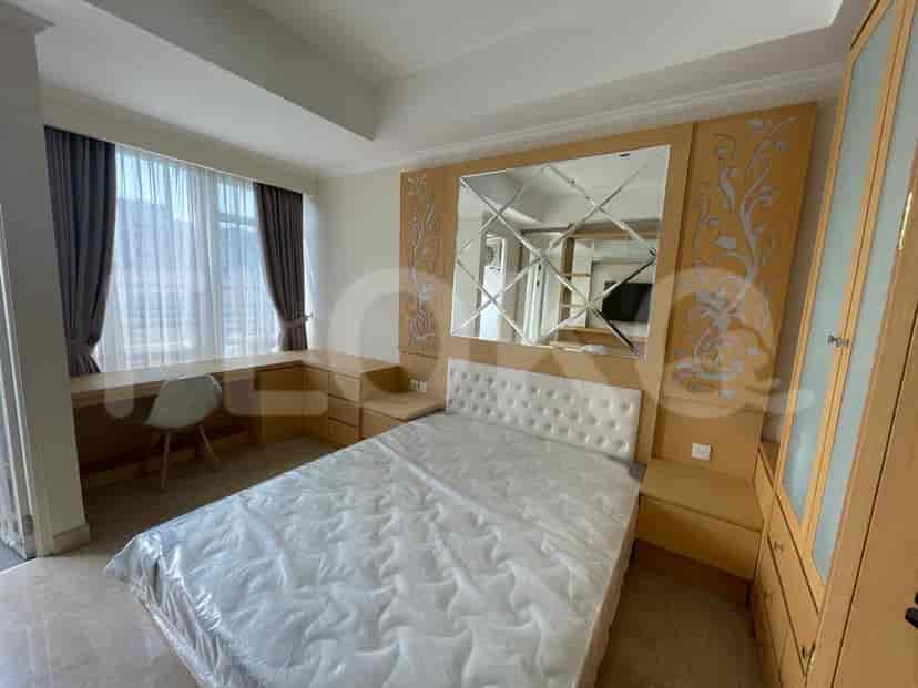 A bedroom with a bed, desk, and a window with curtains.