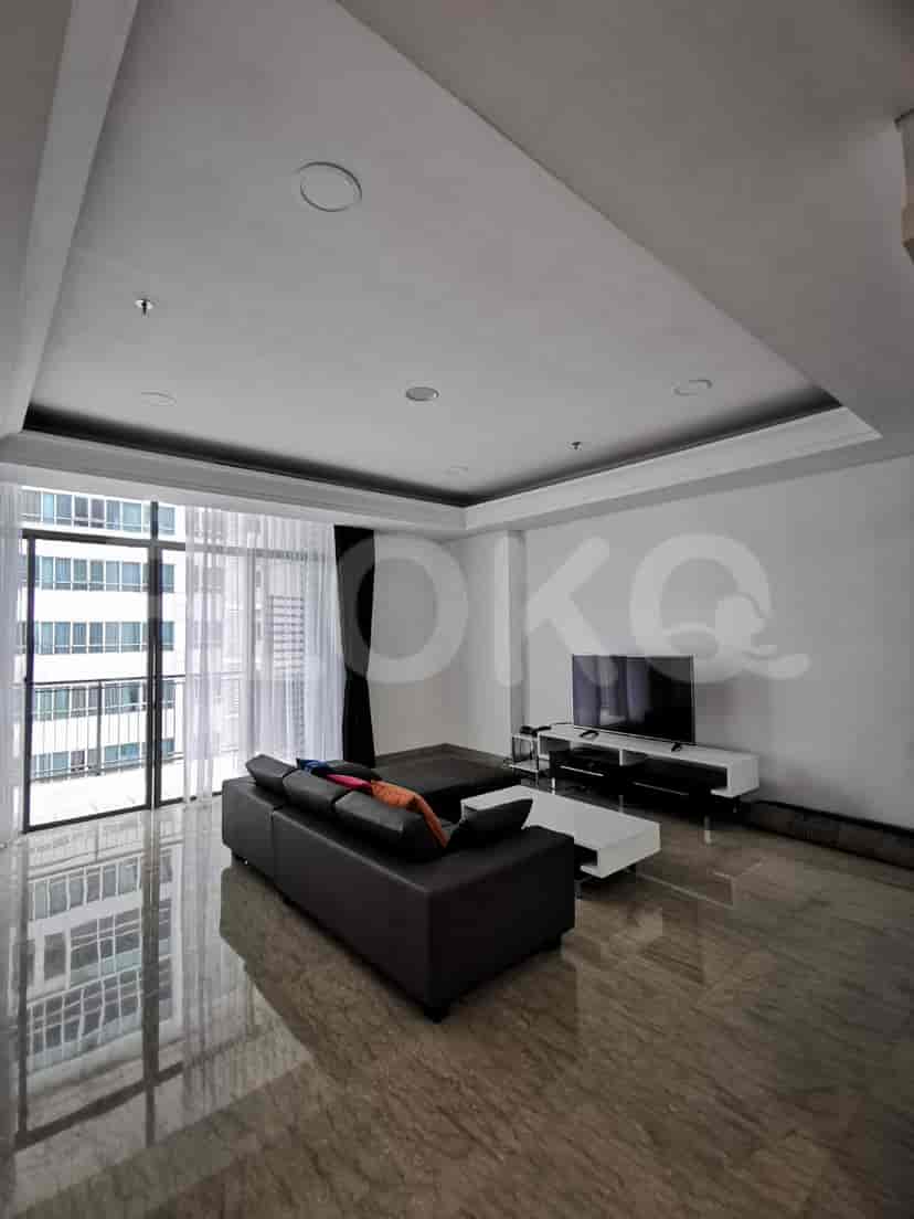 A modern living room with a large L-shaped sofa, TV, and city view.