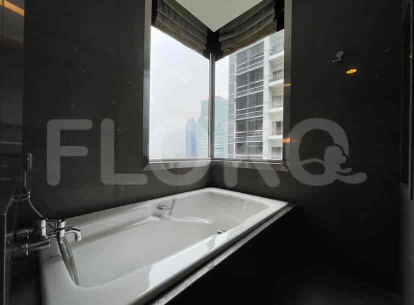 Kamar mandi dengan bathtub, jendela, dan ubin gelap.